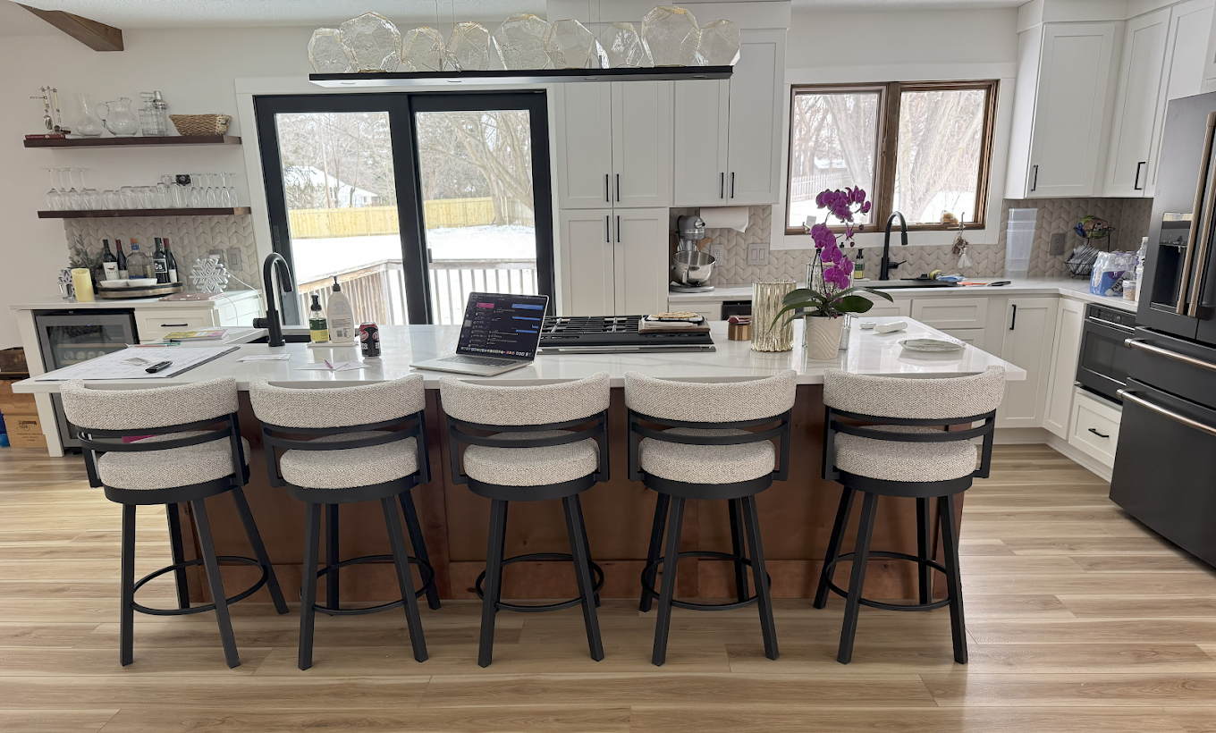 Luxury kitchen remodeling with oversized quartz island, custom white cabinets, black fixtures, bar seating, premium appliances, and open-concept design by Next Level Remodeling MN.